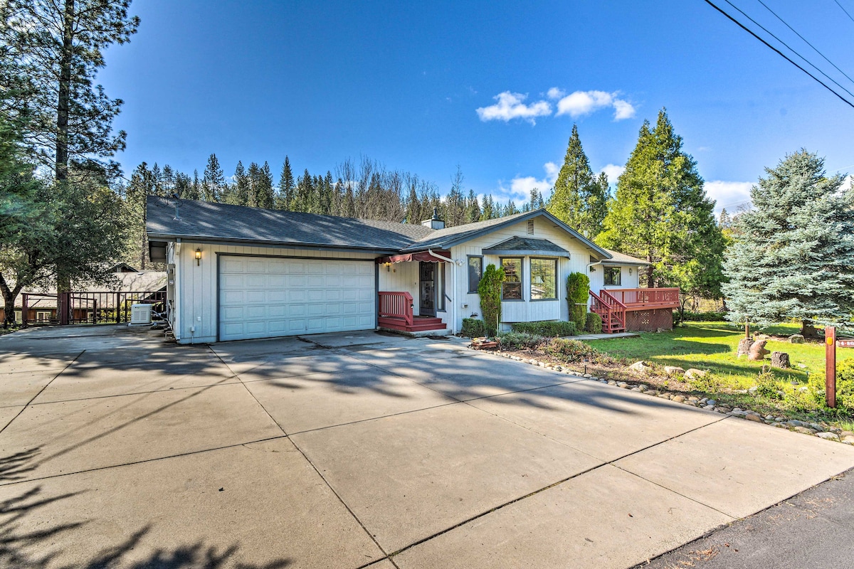 A single-story home is displayed from the front, showcasing a garage and a welcoming entrance with steps leading up to the porch. The surrounding area features trees and greenery, providing a serene outdoor environment.