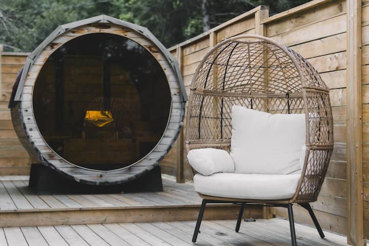 The cottage’s outdoor barrel sauna beside a hanging chair
