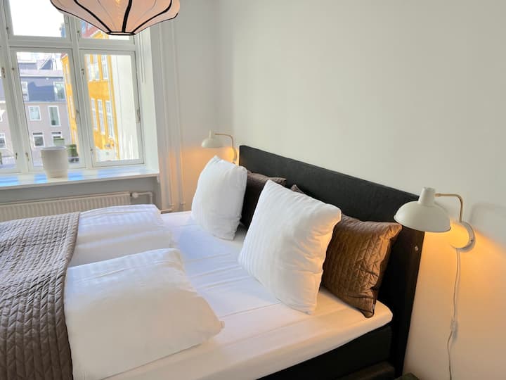 Საძინებელი ორადგილიანი საწოლით. Შავი საწოლის ჩარჩოები ქმნის განსაცვიფრებელ კონტრასტს თეთრ კედლებთან, რაც საძინებლებს თანამედროვედ და სასიამოვნოდ აგრძნობინებს თავს.