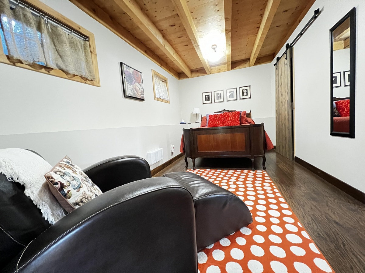 Slaapkamer beneden met tweepersoonsbed, kast, tv met Firestick, zithoek en volledige spiegel.