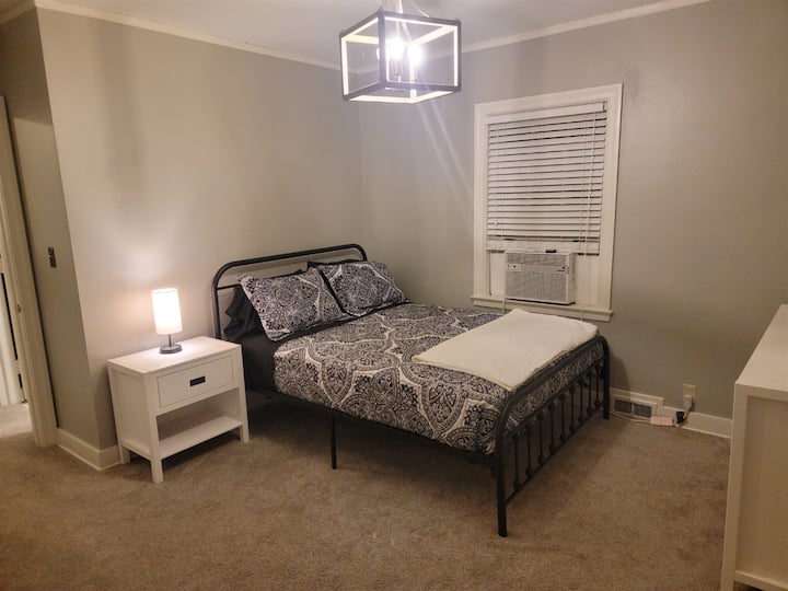 غرفة نوم بسرير بحجم كوين مع خزانة ملابس وطاولة جانبية بجانب السرير