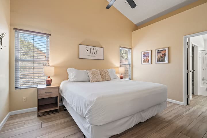 Our spacious primary ensuite bedroom. Stay cool beneath the gentle breeze of a ceiling fan in a room adorned with high ceilings. This combination not only enhances airflow but also adds an open and airy feel to the space.