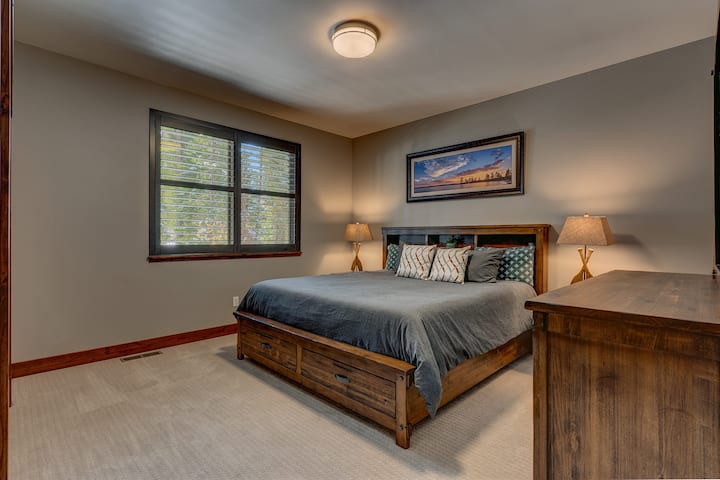 – Spálňa s manželskou posteľou a rustikálnym dreveným rámom  
– Mäkké osvetlenie a nástenné umenie dodávajú útulnú atmosféru.  
– Veľké okno s výhľadom na les a slnečné svetlo