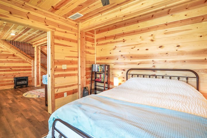 Bedroom: Embrace nature in this charming wood-paneled retreat with cozy lighting and books to enjoy!