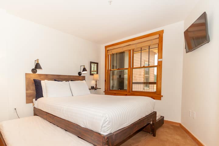 The guest bedroom features a queen-sized bed with two twin trundles and a mounted flat screen TV.