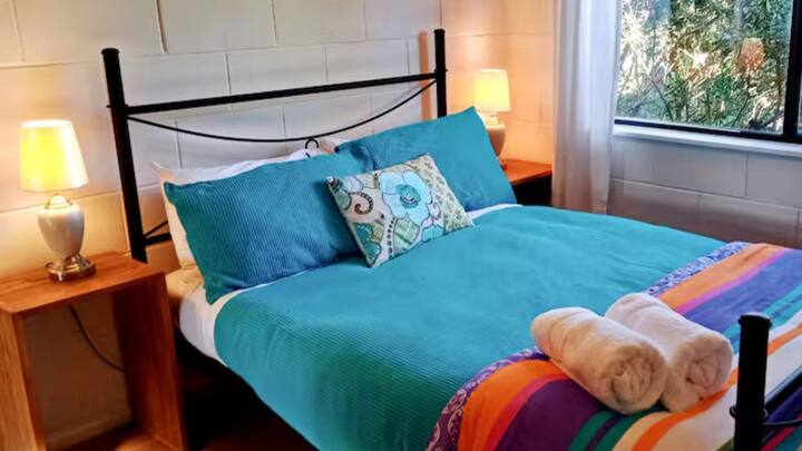 Dulce dormitorio doble con cama cómoda y lámparas activadas por tacto con segundo inodoro en lavandería contigua