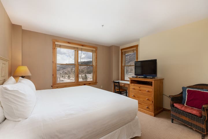 La chambre principale dispose d'un lit king size avec une literie blanche ivoire et d'une télévision à écran plat.