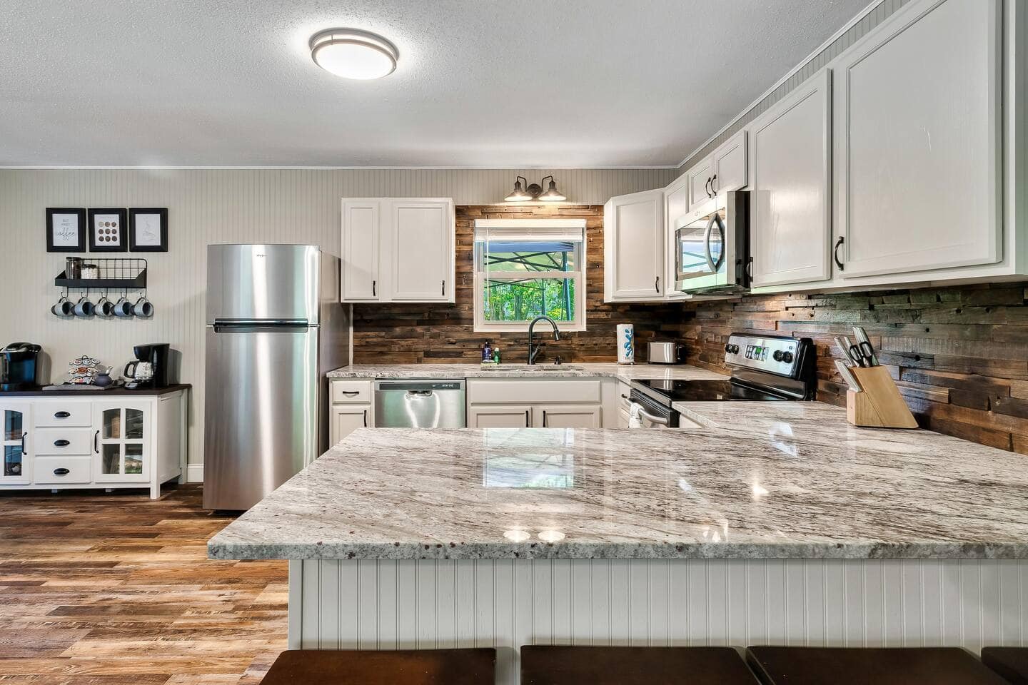 Kitchen with granite island, stainless appliances and reclaimed-wood backsplash