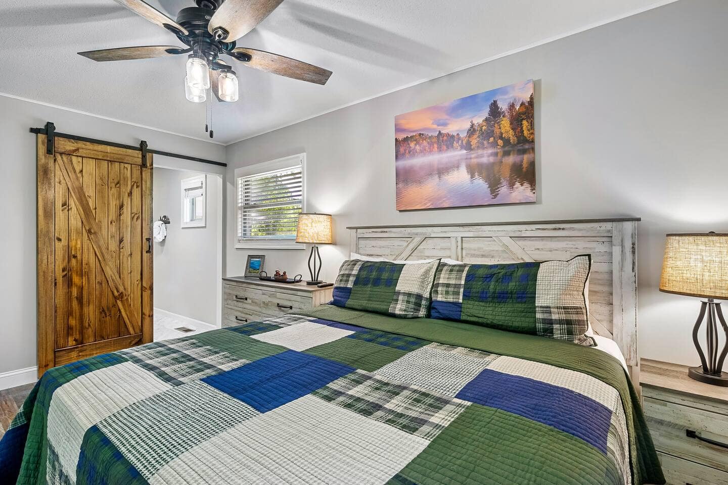 Master bedroom with king bed, sliding barn door, and framed lake artwork