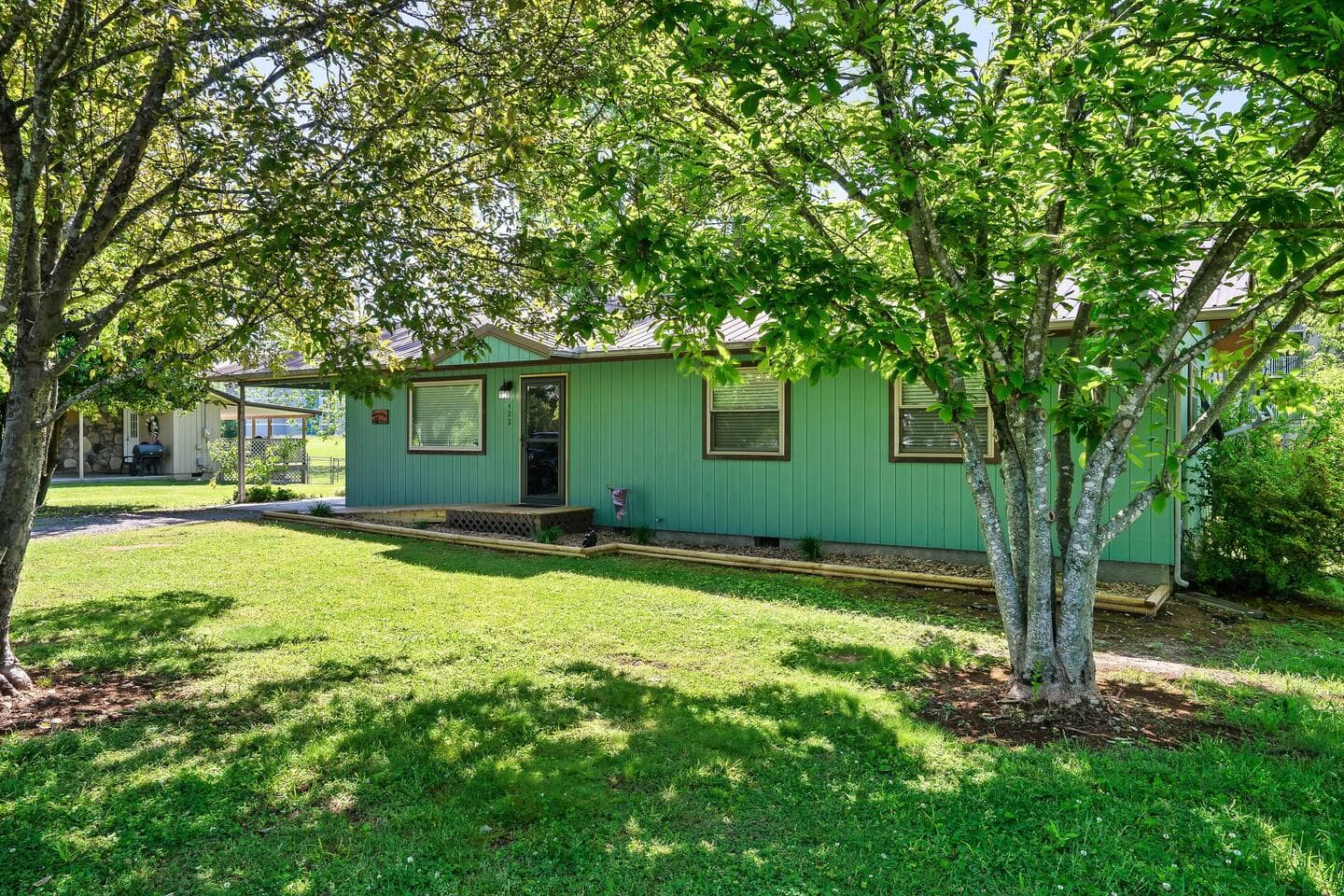 The Asbeary Cottage exterior, a single-level cottage under a large shade tree