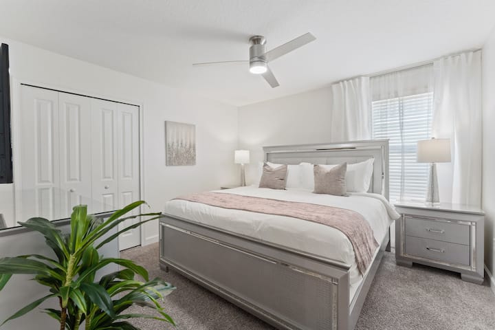 The fourth bedroom is inviting, with a plush king-sized bed topped with soft pillows and a cozy throw blanket.