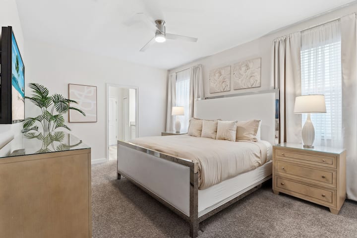 This room has a king-sized plush bed in neutral tones combined with plenty of soft pillows. The natural light in the room gives a bright and relaxing feel, making it a perfect blend of elegance and comfort.