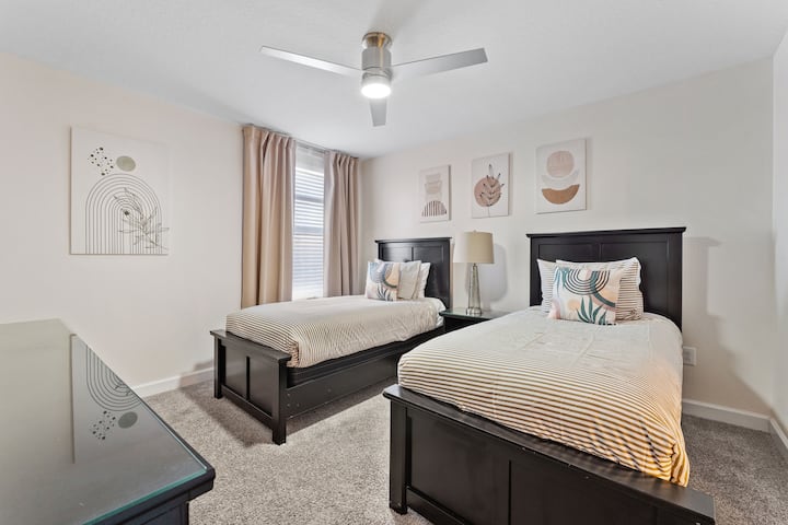 This cozy bedroom features two single beds. The earthy colors of the wall add a relaxing vibe, while the large window fills the room with natural light, ideal for a calm and comfortable shared space.