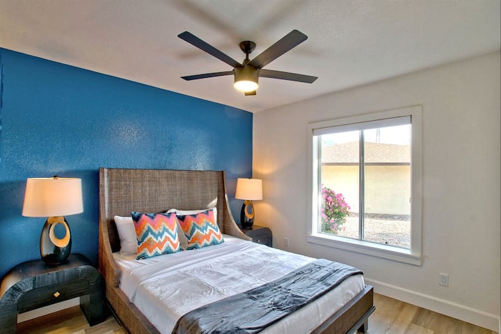 Amplio segundo dormitorio con cama tamaño queen y pared decorativa azul vivo.