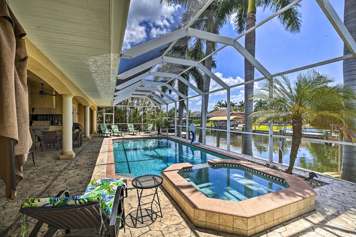 A screened-in patio features a sparkling pool and spa, surrounded by lounge chairs and palm trees. The outdoor space overlooks a peaceful canal, providing a serene backdrop. Natural light floods the area through the expansive, transparent screening.