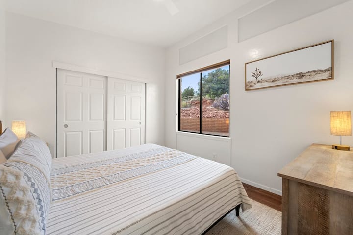 El segundo dormitorio tiene una cama grande y vistas a la naturaleza por la ventana.