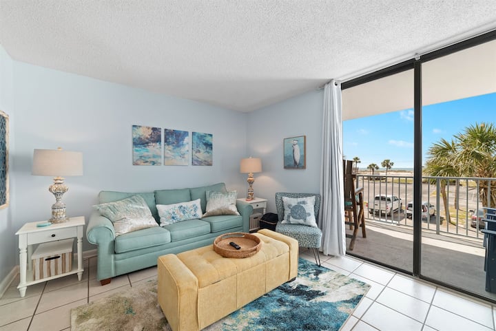 Sehemu ya kuishi yenye starehe yenye sofa ya kuvuta nje kwa ajili ya wageni wa ziada. Chumba hiki cha starehe kina mandhari ya pwani yenye mwanga na hewa safi na kinafunguka kwenye roshani yenye mandhari nzuri ya bahari.