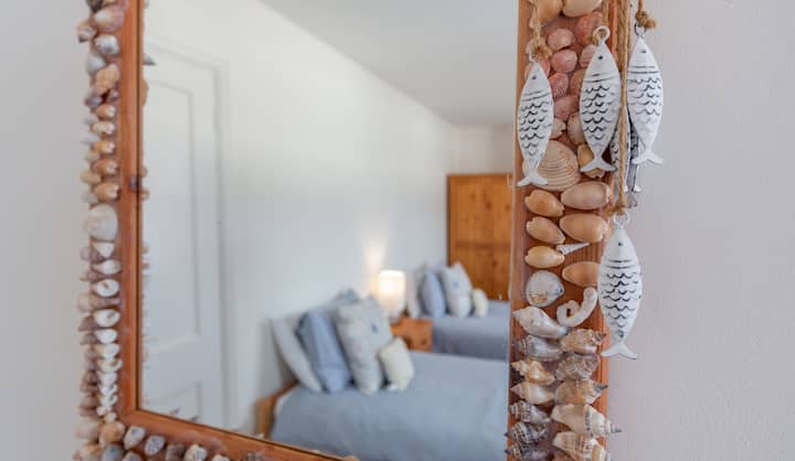 Слика од тематско приморско тематично огледало со одраз на два единечни кревета во Сент Елмо, Саутволд, Сафолк