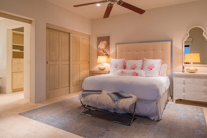 Veliki krevet s klupom ispred, okružen s obje strane pored noćnih ormarića.