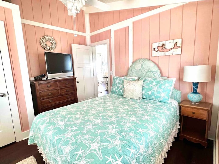 Druhá spálňa so stropným ventilátorom, pohodlná manželská posteľ Queen, nočný stolík a komoda, televízor s Roku a okenné tienidlá na spanie. 