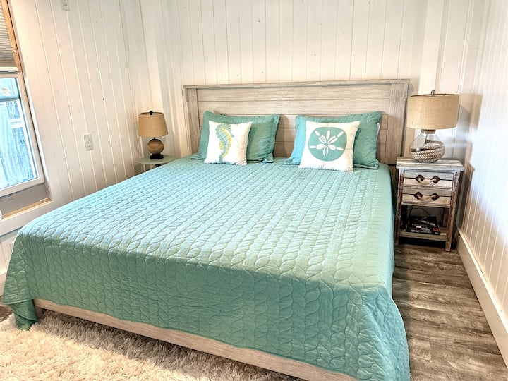 Štvrtá spálňa s nástenným ventilátorom, luxusnou manželskou posteľou, okenným tieňom na spanie a televízorom na relaxáciu.