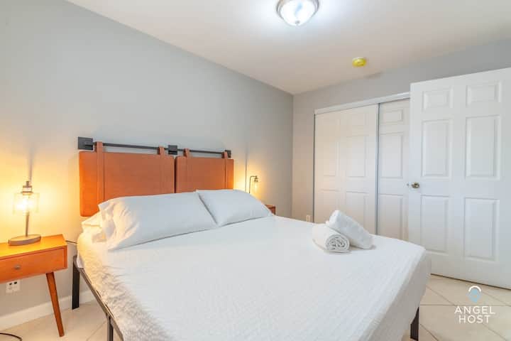 The bedroom features a queen bed and simple minimalistic design.