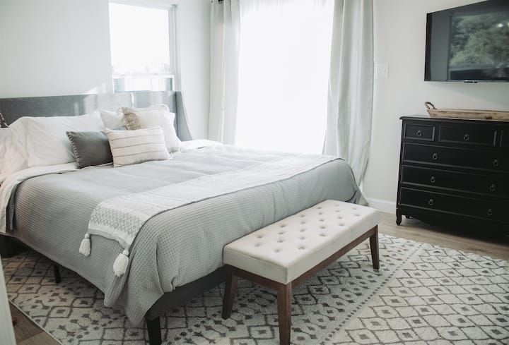 Მეფე საძინებელი მაღლა ღია სააბაზანოთი და ცალკე გემბანის შესასვლელი ბისტროს მაგიდით.