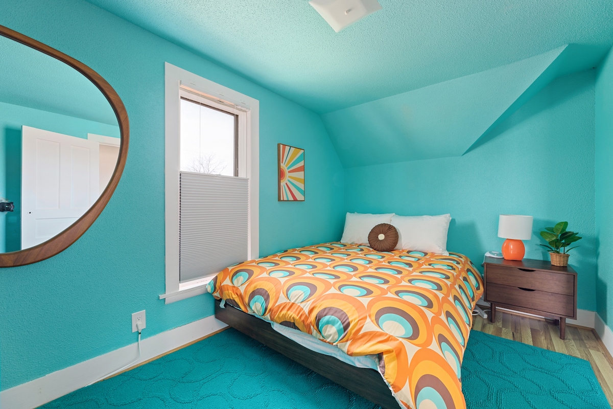 La chambre 2 dispose d'un lit queen confortable, avec une télévision connectée, des ports de recharge USB et une atmosphère bleue vif et accueillante.