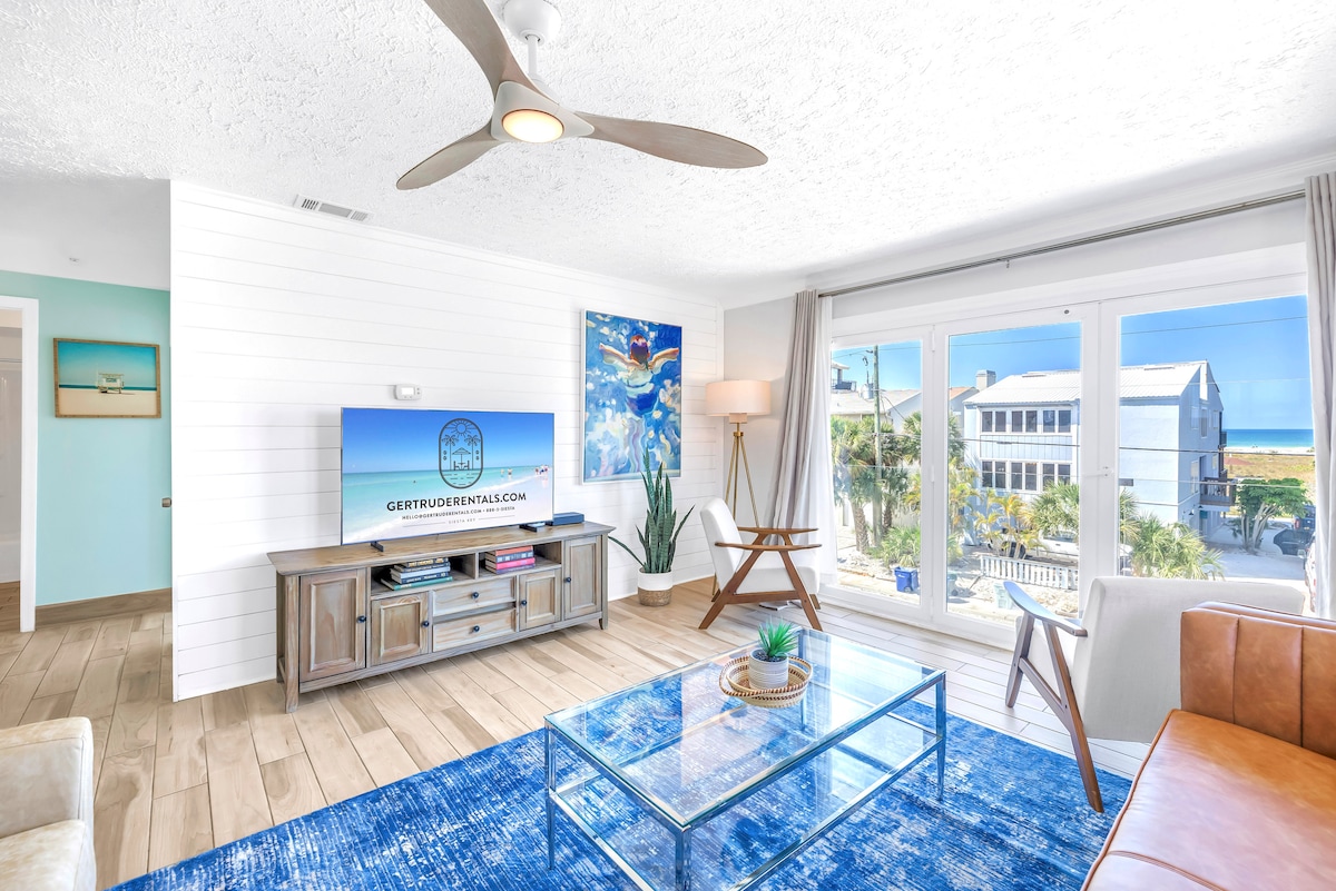 Sehemu angavu ya kuishi yenye televisheni mahiri, mapambo maridadi na madirisha makubwa yanayoangalia Ufunguo wa Siesta.