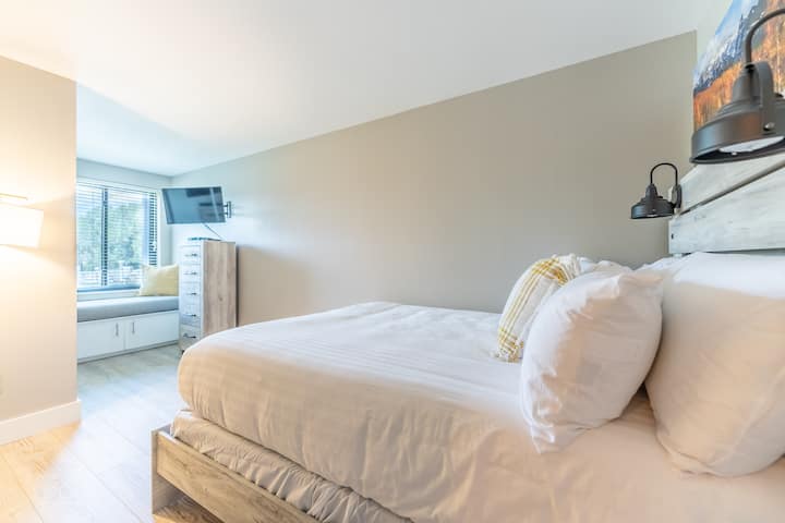 Dormitorio de invitados con una cama tamaño queen y un rincón para sentarse junto a la ventana. 