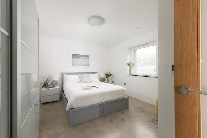 बेडसाइड टेबल और लैंप के साथ किंग साइज़ का बेड - ट्रेहेल