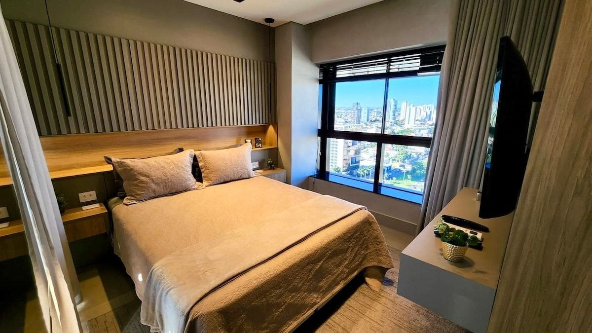 วิวห้องพักพร้อมเตียงควีนไซส์สมาร์ททีวีและงานไม้อันงดงามที่หัวเตียงที่มีหน้าต่างด้านหลัง