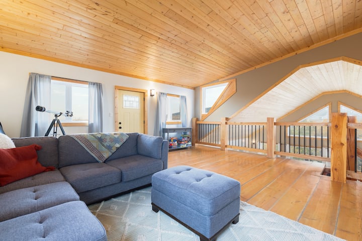 Relax in the top-floor loft area with sectional couch, TV, board games, and warm wood flooring