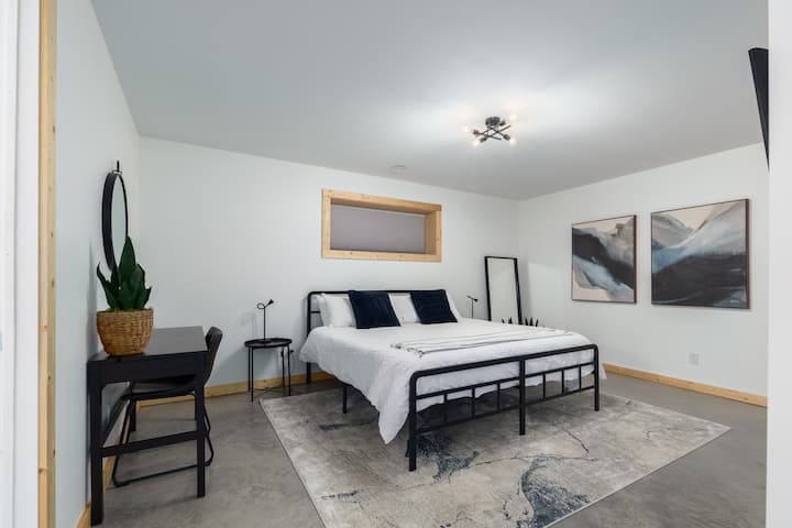 Basement king bedroom with piles of space, wall-mounted TV, and attached ensuite bathroom