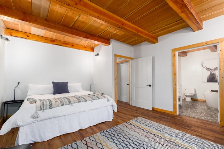 Mainfloor king bedroom with attached 'spa' bathroom with freestanding tub and custom stone flooring