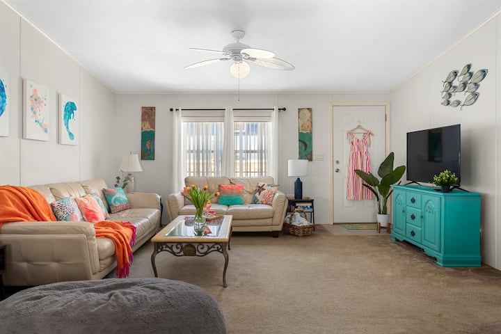 The den features two comfy leather couches, coffee tables, lamps, and carpet to keep it cozy for sleeping on the floor mattress in the grey pouf!