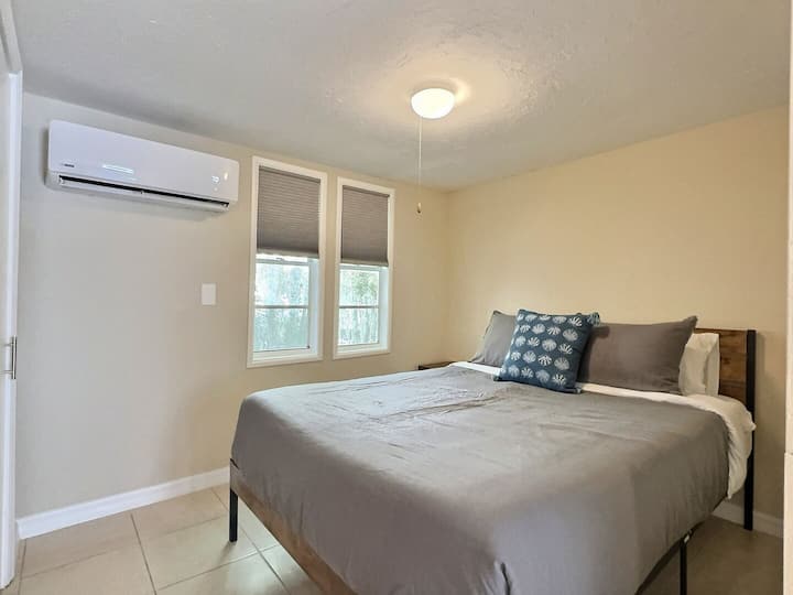 Удобна спалня с голямо легло, нощни шкафчета и прозорец.