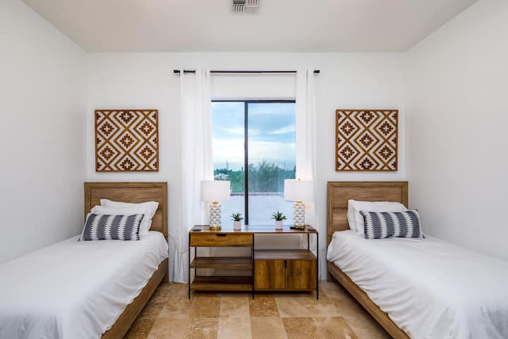 El dormitorio 2 cuenta con dos camas individuales, una elegante decoración del suroeste y una puerta de conexión a la suite principal, ideal para familias o amigos que viajan juntos.