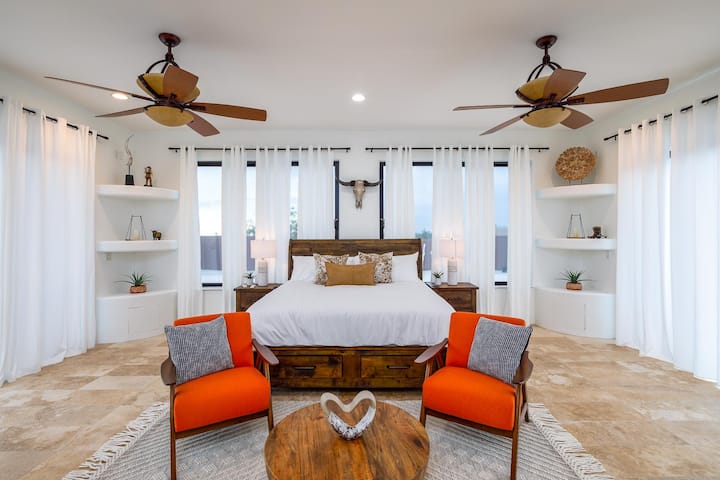 Relájate en la espaciosa suite principal con una cama tamaño king, atrevidos toques de color y serenas vistas a la montaña a través de ventanas altas con cortinas blancas que fluyen.