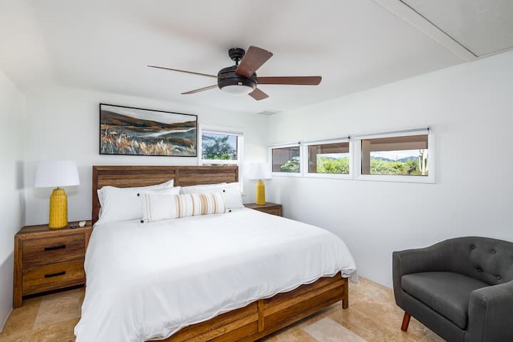 El dormitorio 6 cuenta con una cama tamaño king, iluminación vibrante y vistas panorámicas a la ventana. Un medio baño cercano agrega comodidad adicional para tu grupo.