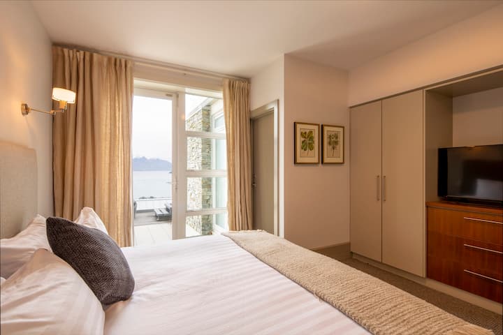 Tercer dormitorio privado: disfruta de comodidad y privacidad en este espacioso dormitorio con baño privado, acceso directo a una terraza e impresionantes vistas al lago y a las montañas.