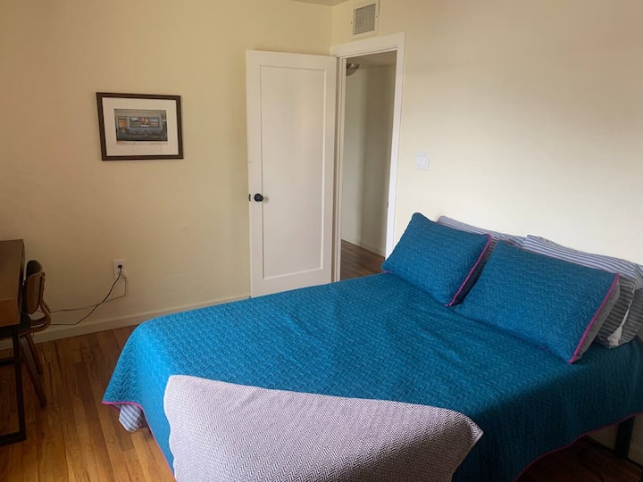 تحتوي غرفة النوم الوسطى على سرير مزدوج الحجم وأدراج خزانة ملابس ومكتب مع شاشة كمبيوتر.