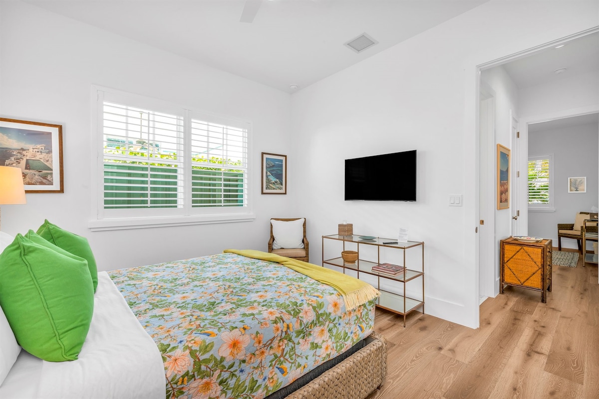 Este dormitorio cuenta con una cama tamaño queen con plataforma de ratán, mesas auxiliares con elegantes lámparas altas y dos hermosas impresiones enmarcadas de Slim Aarons. ¡Un montón de espacio del armario! La dulce colcha floral y estampada de pájaros es un toque encantador de la habitación.