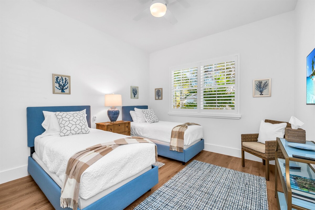 Este dormitorio cuenta con dos ricas camas de plataforma tapizadas de color azul. Tonos clásicos de blues, cremas y beiges en todas partes.