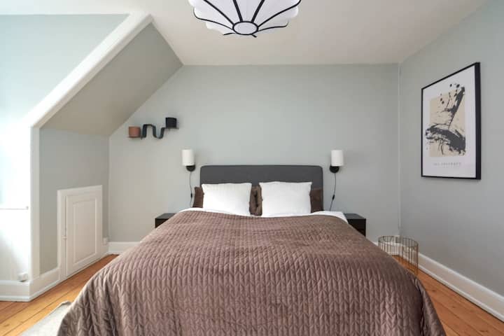 Chumba hiki cha kulala kina kitanda maradufu chenye rangi ya kijivu, kilicho na rangi ya hudhurungi kwa ajili ya joto na starehe ya ziada.