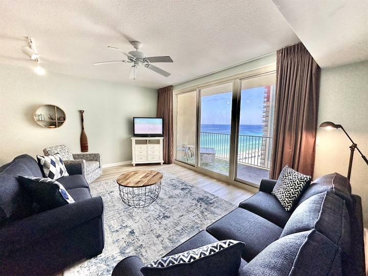 Sala de estar frente a la playa con vistas al golfo del piso al techo, televisor inteligente y nuevo sofá cama para relajarse después de los días de playa.