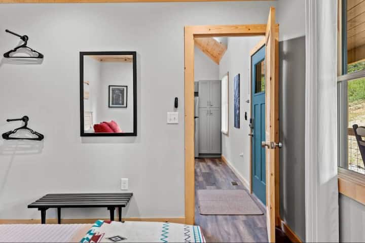 Dormitorio principal con espejo, banco y espacio para colgar la ropa.