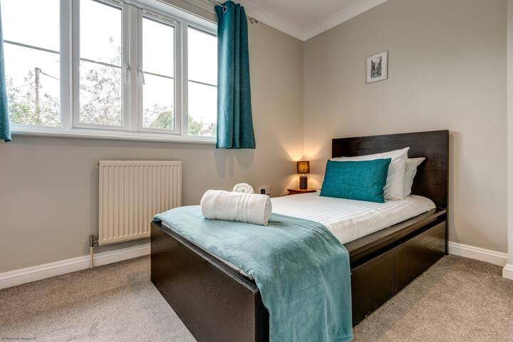 Une chambre lumineuse au Didcot Whitehouse avec un lit confortable, des lampes de chevet et une ambiance fraîche et moderne.