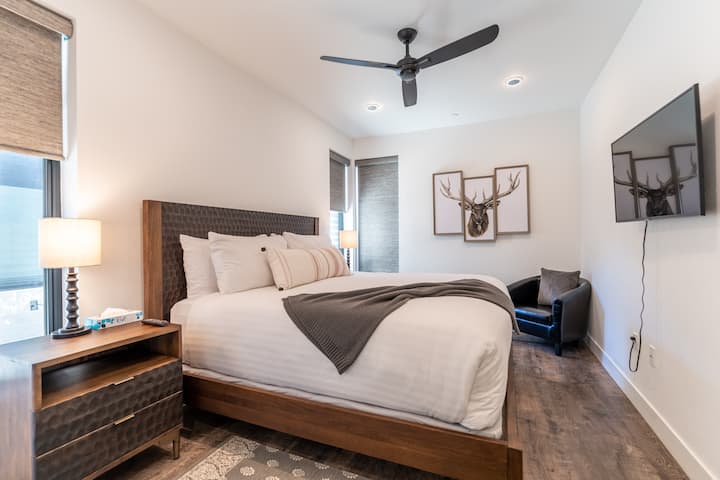 Chumba cha msingi chenye nafasi kubwa chenye kitanda cha ukubwa wa King, Televisheni mahiri iliyowekwa na hifadhi nyingi. 