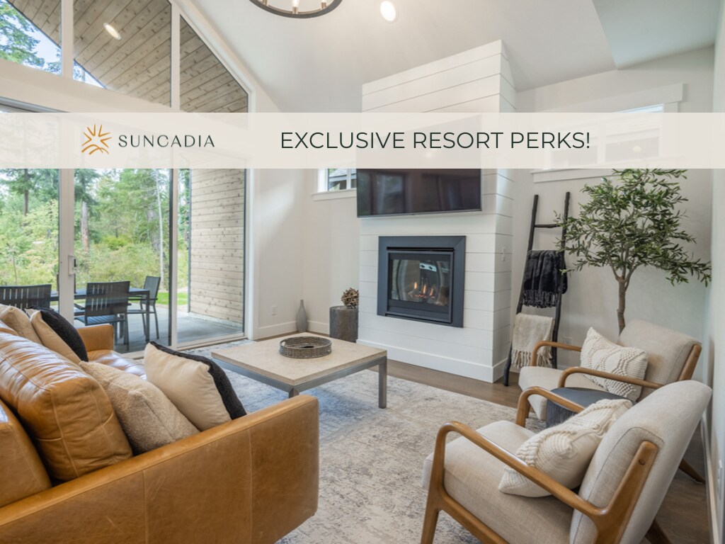 A cozy living area features a modern fireplace, which is framed by a sleek, white shiplap wall. Large windows allow natural light to illuminate the space, while comfortable seating and a simple coffee table create an inviting atmosphere for relaxation.